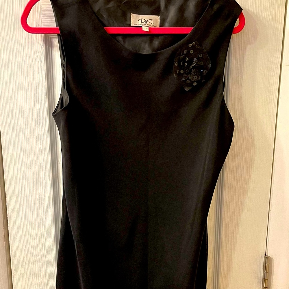 Simple black dress for evening or a wedding. Sleeveless,cute flower, cute hem.
